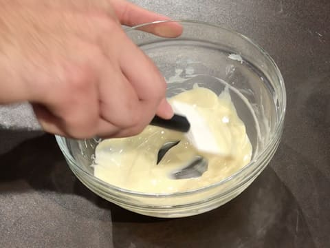 Mélange du chocolat blanc fondu dans un saladier en verre, à l'aide d'une spatule maryse