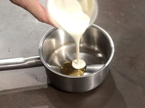 La crème fleurette est versée sur le miel dans une casserole posée sur le plan de travail