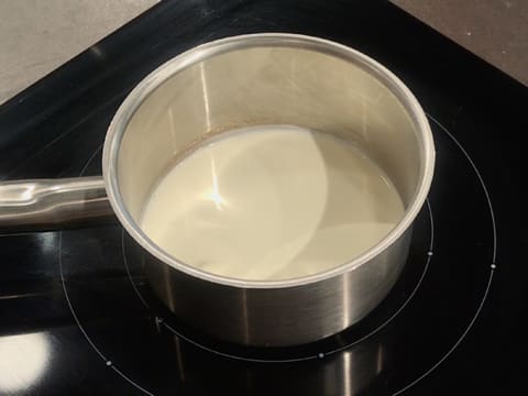 La casserole contenant la crème liquide et le miel est posée sur une plaque de cuisson