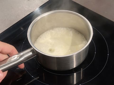 La crème fleurette et le miel sont en ébullition dans la casserole qui est sur la plaque de cuisson