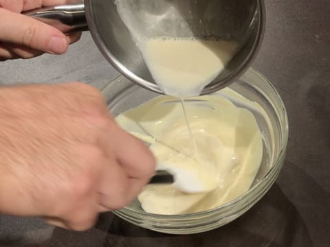 La crème au miel chaude est versée sur le chocolat blanc fondu dans le saladier en verre, le tout mélangé avec la spatule maryse