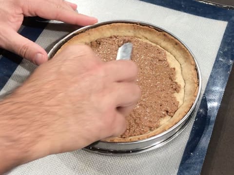 Le croustillant noix de pécan est étalé avec une mini spatule coudée sur le fond de tarte cuit dans le cercle inox, le tout posé sur le tapis de cuisson en silicone