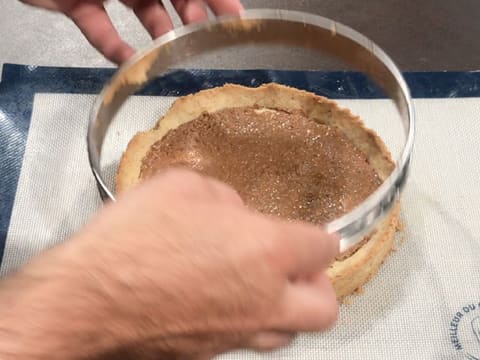 Le cercle à tarte en inox est retiré vers le haut, laissant le fond de tarte cuit recouvert de croustillant noix de pécan, posé sur la toile en silicone