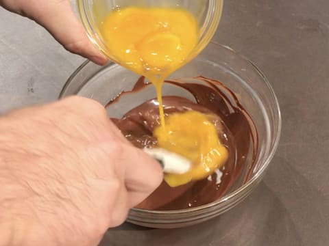 Ajout des jaunes d'oeufs sur le chocolat noir fondu dans le bol en verre