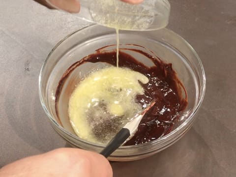 Ajout du beurre fondu dans la préparation chocolatée dans le bol en verre