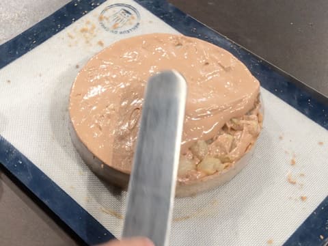 La mousse au chocolat est étalée à la surface de la tarte à l'aide d'une spatule métallique coudée