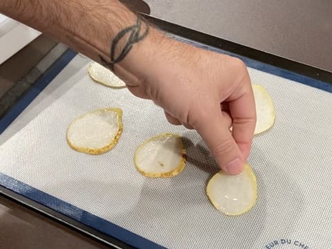 Des tranches de poire sont déposées sur une plaque à pâtisserie recouverte d'un tapis en silicone