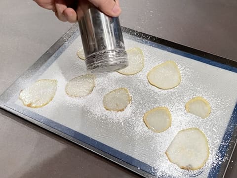 Du sucre glace est saupoudré sur les tranches de poire qui sont placées sur le tapis de cuisson