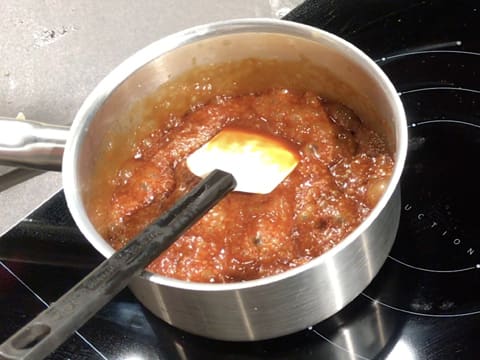 La sauce caramel est en train de bouillir dans la casserole qui est sur la plaque de cuisson