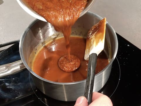 La sauce caramel est versée dans la casserole qui contient le caramel de miel