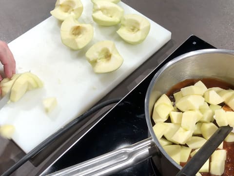 Les pommes épluchées et coupées en gros morceaux sont placées dans la casserole qui contient le caramel
