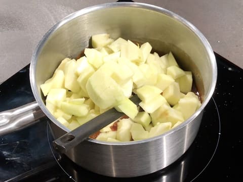Les pommes épluchées et coupées en gros morceaux sont dans la casserole qui est sur la plaque de cuisson