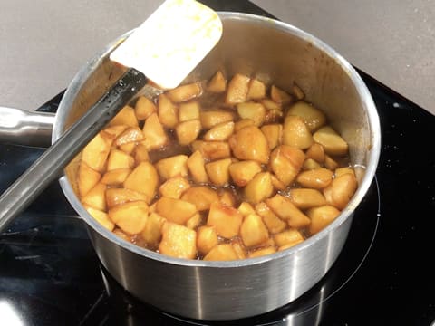 Obtention des morceaux de pommes caramélisés dans la casserole qui est sur la plaque de cuisson