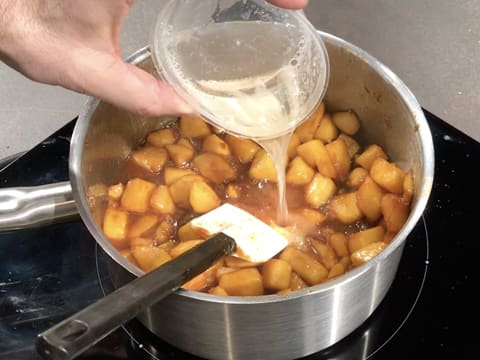 La gélatine hydratée et fondue est versée sur les morceaux de pommes et le caramel dans la casserole