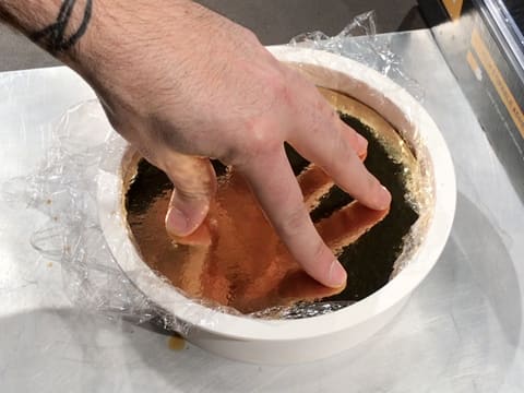 Un support à gâteau rond et doré est posé dans le moule silicone rond qui est sur la plaque à pâtisserie