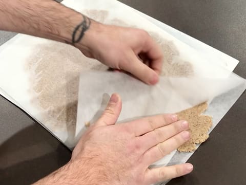 La feuille de papier sulfurisé qui recouvre la pâte à streusel est partiellement retirée
