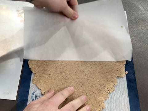 La pâte à streusel est retournée sur le tapis de cuisson silicone et la feuille de papier sulfurisé du dessus est retirée