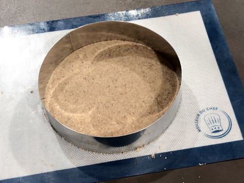 Le cercle à mousse encadre le disque de pâte à streusel sur le tapis de cuisson silicone