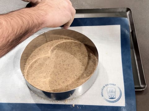 Le tapis de cuisson silicone sur lequel se trouvent le disque de pâte à streusel et le cercle à mousse, est glissé sur une plaque à pâtisserie