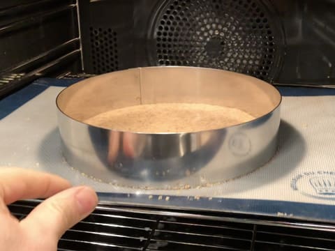 La plaque à pâtisserie contenant la pâte à streusel et le cercle à mousse sur le tapis de cuisson silicone, est placé dans le four