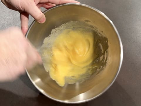 Les œufs et le sucre en poudre sont blanchis à l'aide du fouet dans le cul de poule