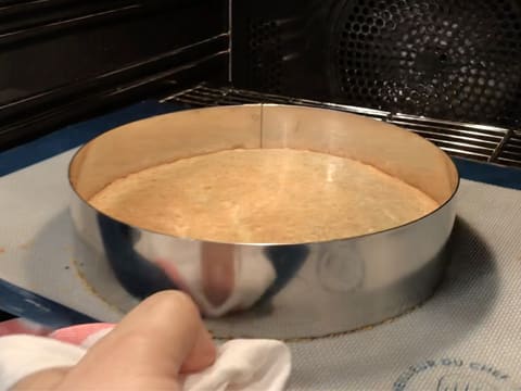 La préparation de moelleux aux noisettes dans le cercle à mousse est cuite et le tout posé sur le tapis de cuisson silicone sortent du four