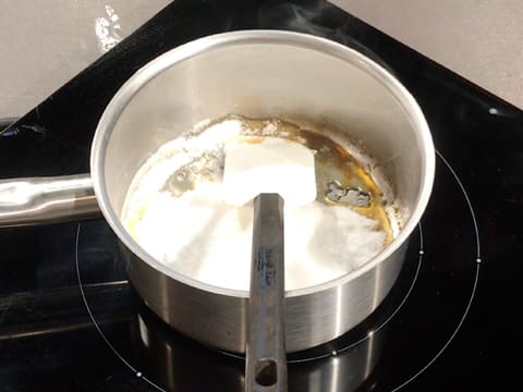 Le sucre en poudre commence à se transformer en sirop dans le fond de la casserole qui est posée sur la plaque de cuisson