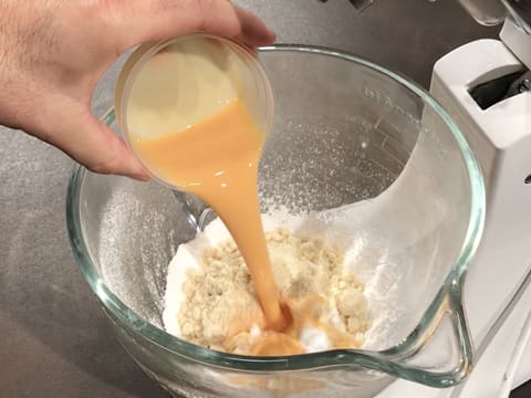 Ajout des oeufs entiers battus sur la poudre d'amandes et le sucre glace tamisé dans la cuve du batteur électrique