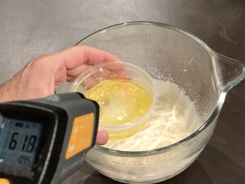 Prise de la température du beurre fondu dans un petit récipient, à l'aide du thermomètre à visée laser qui affiche 61,8°C