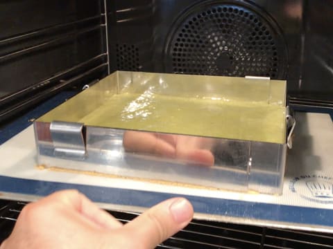 La plaque à pâtisserie contenant la toile en silicone et le cadre inox dans lequel se trouve la pâte à biscuit thé matcha, est placée dans le four à mi hauteur