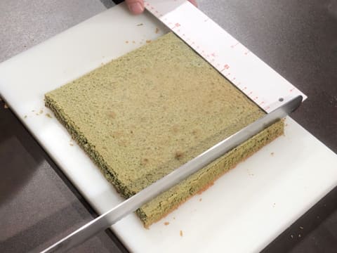 Un côté du biscuit thé matcha est arasé à l'aide d'un couteau-scie à génoise sur une planche à découper avec la règle graduée qui indique 20 cm