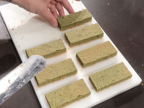 Les rectangles de biscuit thé matcha sont écartés les uns des autres et placés sur la largeur de la planche à découper avec une spatule métallique