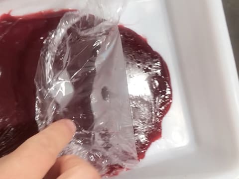 La feuille de papier film est retirée du confit de framboise qui se trouve dans le bac alimentaire