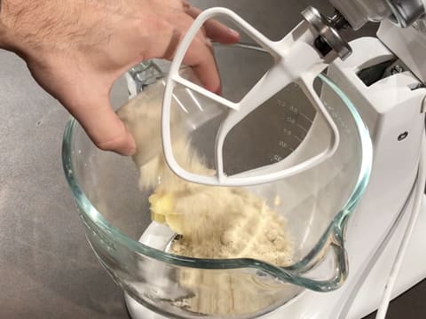 Ajout de la poudre d'amandes sur la cassonade et le beurre pommade dans la cuve du batteur électrique qui est muni de l'accessoire feuille