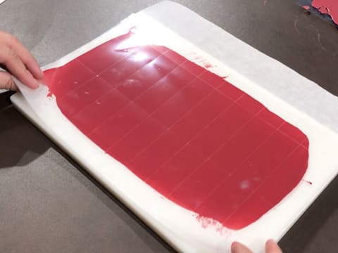 Obtention des plaquettes de chocolat taillées dans la bande de chocolat inspiration framboise cristallisé sur la feuille de papier sulfurisé