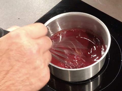 La préparation à la framboise est mélangée au fouet dans la casserole qui est placée sur la plaque de cuisson