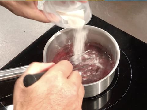Le mélange sucre et pectine NH nappage est versé sur le purée de framboise dans la casserole, tout en étant mélangé au fouet