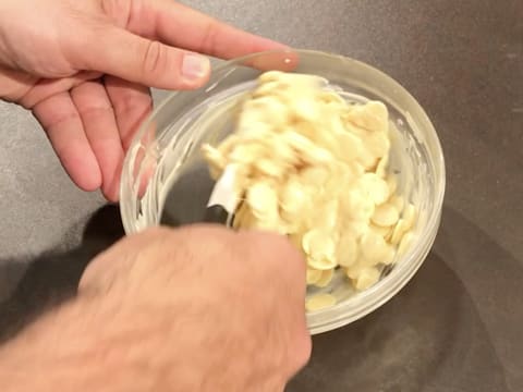 Mélange à la spatule maryse des pistoles de chocolat blanc partiellement fondues dans un grand bol en verre