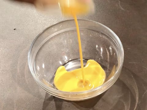 Les jaunes d'oeufs sont versés dans un saladier en verre posé sur le plan de travail