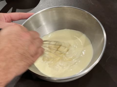 La crème au chocolat blanc est mélangée au fouet dans le cul de poule qui est posé sur le plan de travail