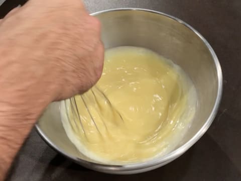 La crème au chocolat blanc est mélangée au fouet dans le cul de poule qui est posé sur le plan de travail