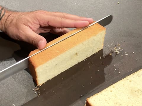 The vanilla sponge cake is trimmed with a serrated knife