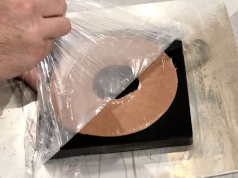 Remove the cling film from the silicone mould with chocolate crémeux