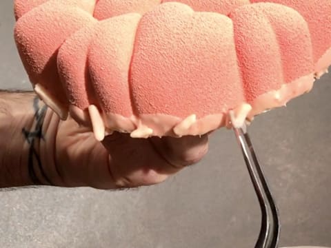 Arrange slivered almonds coated with pink chocolate around the base of the cake