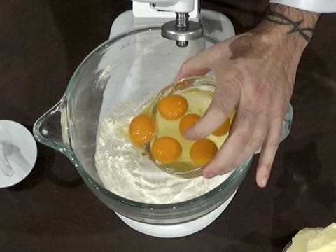 Add the whole eggs over the flour in the bowl