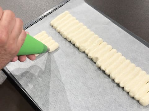 Pipe the lady finger preparation on the baking parchment into parallel lines