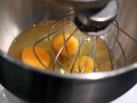 The whole eggs in the stand mixer bowl with the whisk