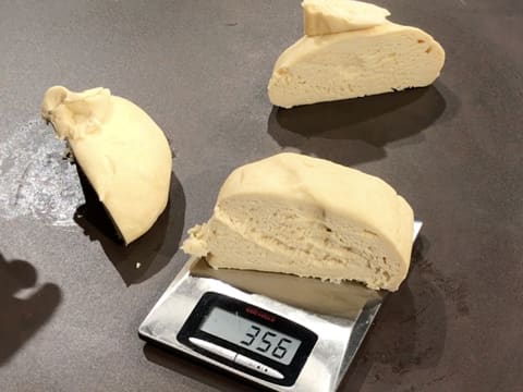 The brioche dough is divided in three equal balls, one dough ball is on the kitchen scale