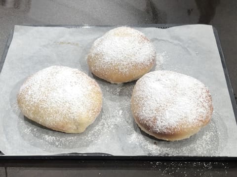 Obtention de trois beignets placés sur des feuilles de papier absorbant et décorés de sucre glace