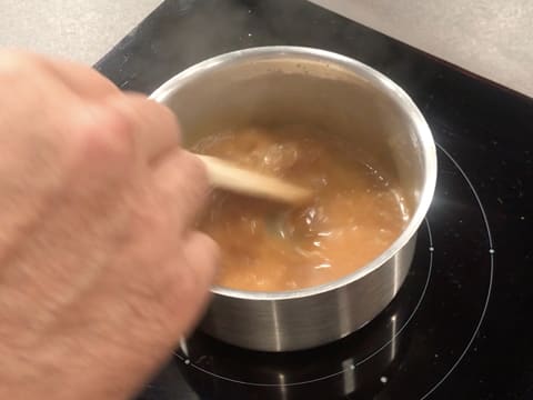 Obtention d'une sauce caramel qui est mélangée à la spatule dans la casserole placée sur la plaque de cuisson